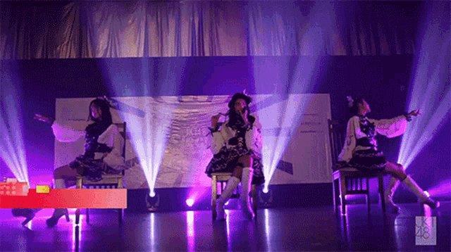a group of girls are performing on stage with purple lights