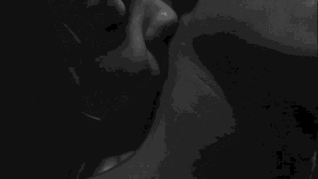 a black and white photo of a man and woman kissing each other .