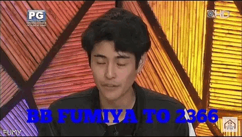 a man is sitting in front of a wall with the words bb fumiya to 3366 written on it