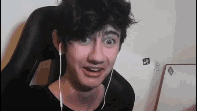 a young man wearing headphones and a black shirt is making a funny face .