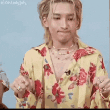 a man wearing a yellow floral shirt and a pearl necklace