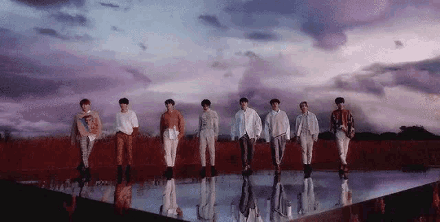 a group of young men are standing next to each other in front of a purple sky .