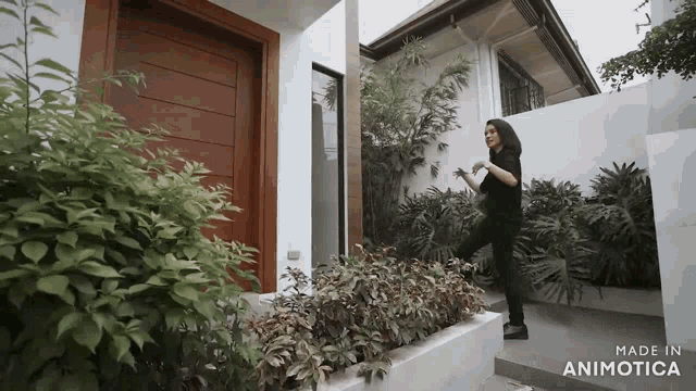 a woman is standing in front of a house with the words made in animotica on the bottom