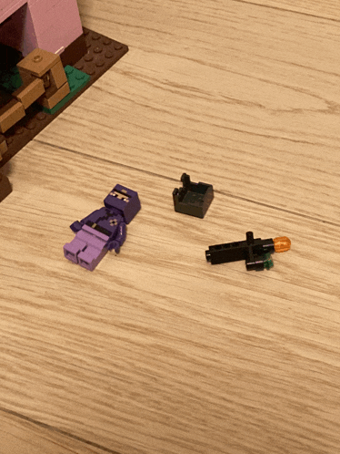 a purple lego figure is laying on the floor next to a gun