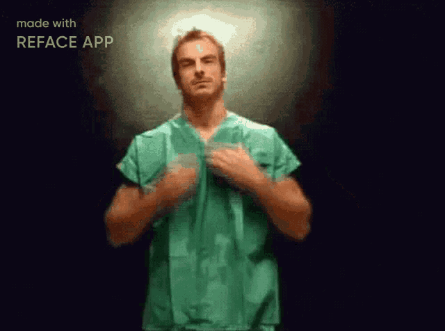 a man in a green scrub is making a gesture with his hands .