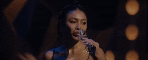 a woman is drinking from a glass in a dark room in a dark room .