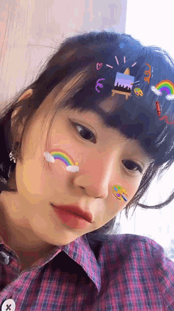 a girl with stickers on her face is wearing a plaid shirt .
