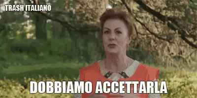 a woman in an orange apron says " dobbiamo accettarla " in front of trees
