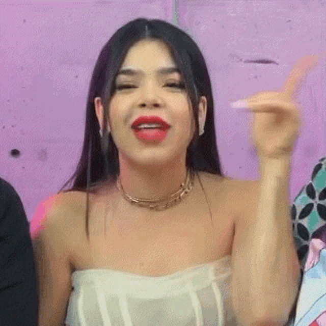 a woman in a white dress and red lipstick is giving a thumbs up sign .