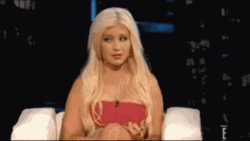 a woman with blonde hair is sitting in a chair with her hands on her knees .