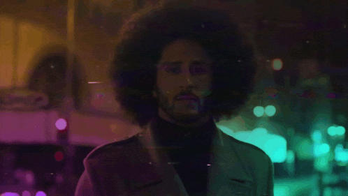 a man with an afro is standing in front of a sign that says ' subway '