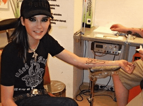 a woman is getting a tattoo on her arm while wearing a shirt that says misso on it