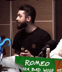 a man is sitting at a table with a sign that says romeo aka bad wolf