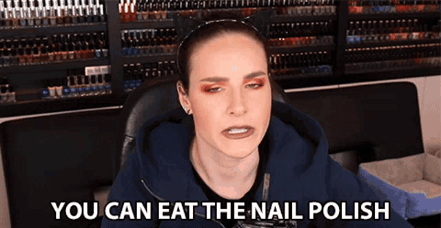 a woman is sitting in front of a wall of nail polish and says you can eat the nail polish