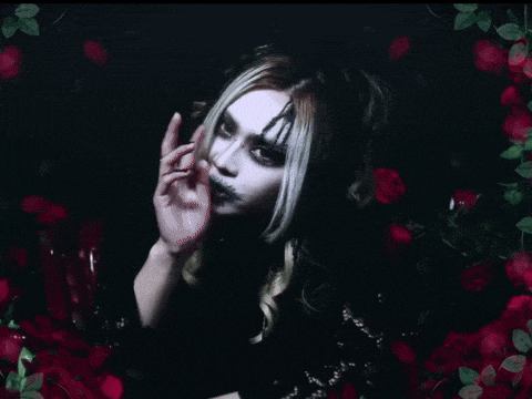 a woman in a black dress is surrounded by roses