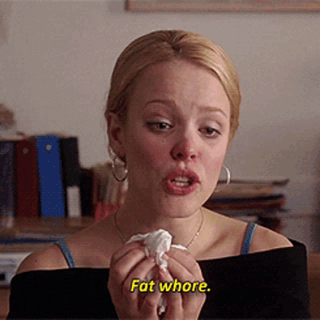 a woman is holding a napkin and says fat whore in yellow letters