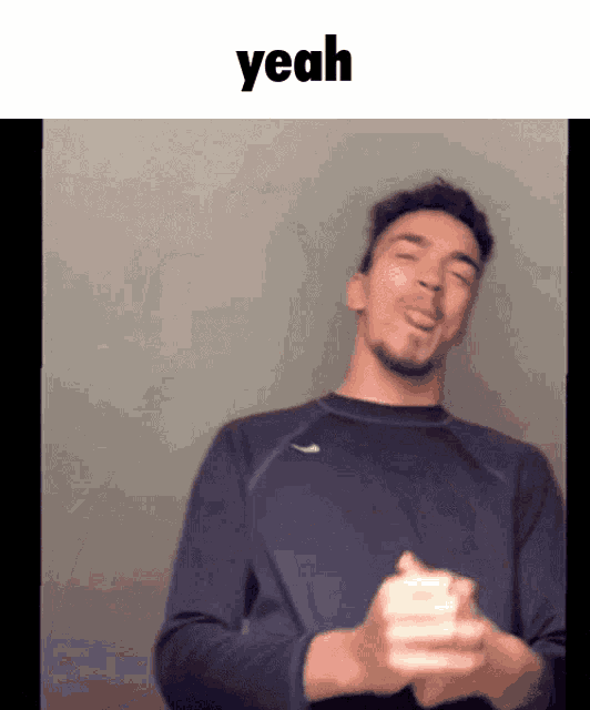 a man in a blue sweater is making a funny face with the word yeah above him