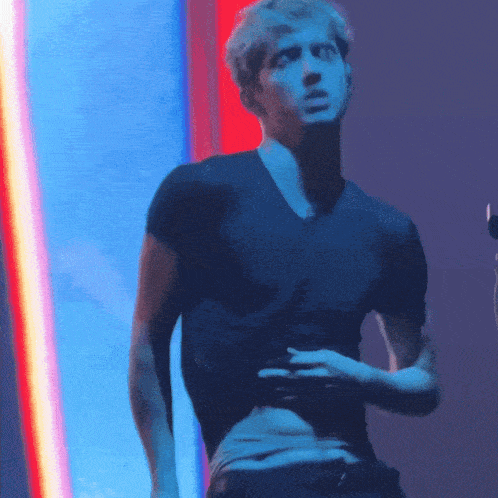 a man in a black shirt stands in front of a blue light