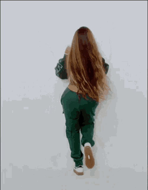 a woman with long hair is standing with her arms outstretched against a wall .