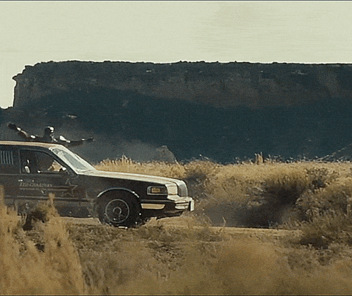 a sheriff 's car is driving through a grassy field