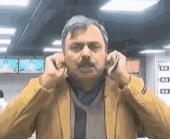 a man covering his ears with his hands while talking on a phone
