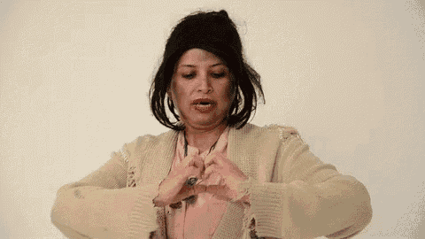 a woman is making a heart shape with her hands .