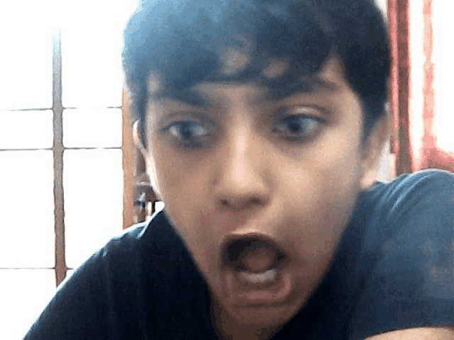 a young boy making a funny face with his mouth wide open