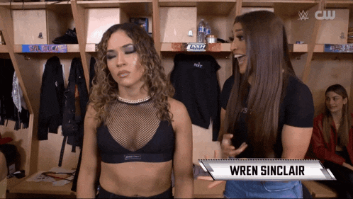 two women are standing in a locker room and the name wren sinclair is on the sign