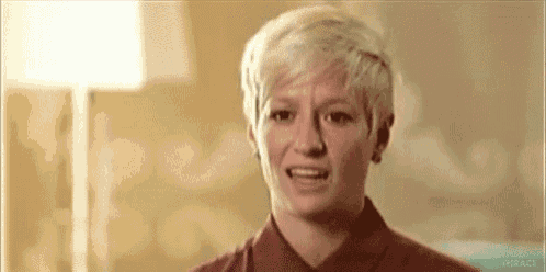 a woman with short blonde hair is making a funny face and looking at the camera .
