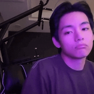 a young man in a purple shirt is sitting in front of a microphone in a room .