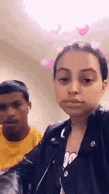 a woman in a leather jacket is taking a selfie next to a boy in a yellow shirt .