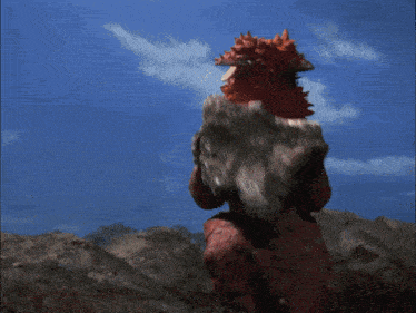 a cartoon character is standing in front of a fire with a blue sky in the background