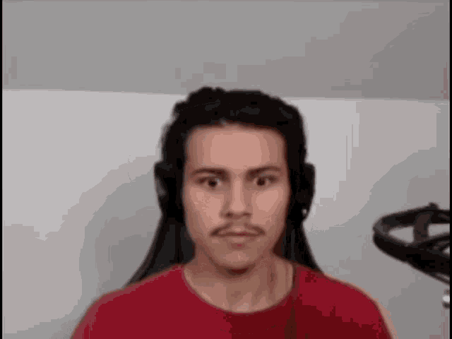 a man wearing headphones and a red shirt is looking at the camera