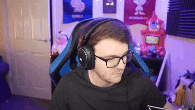 a man wearing glasses and headphones is sitting in a chair .