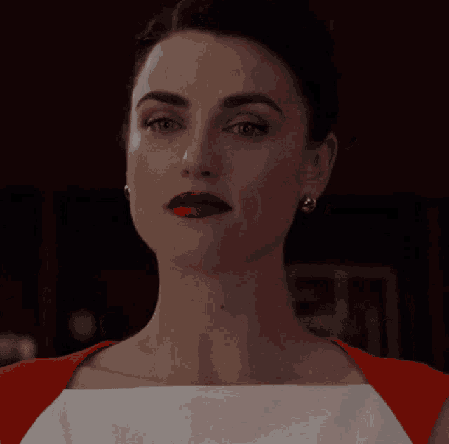 a close up of a woman 's face with red lipstick and gold earrings