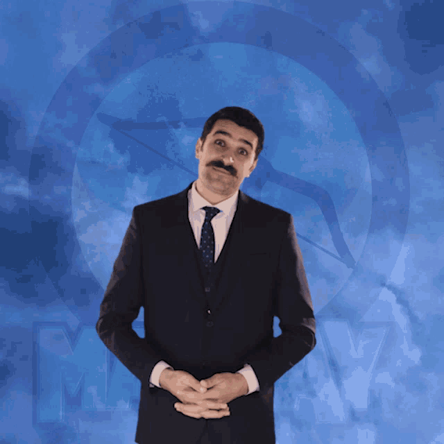 a man in a suit and tie holds his hands on his stomach in front of a blue sky