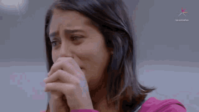 a close up of a woman covering her mouth with her hands with the words los estrellas in the corner
