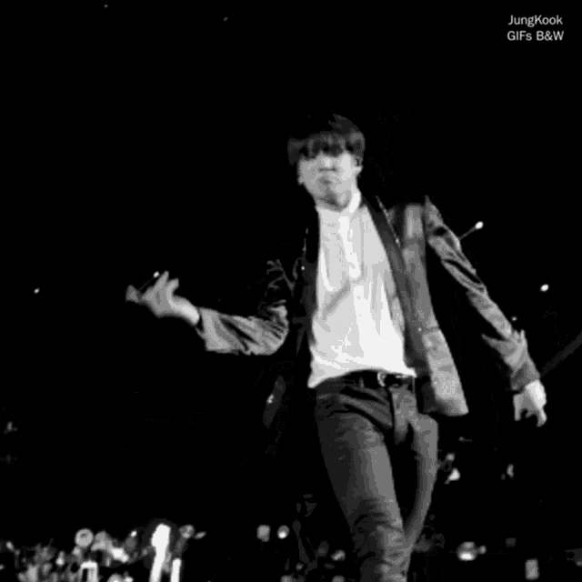 a black and white photo of a man in a suit and tie dancing
