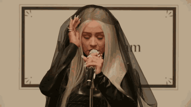 a woman singing into a microphone with a veil on her head