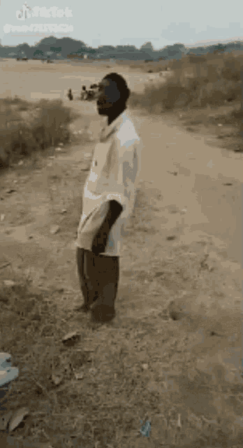a man is standing in the middle of a dirt road .