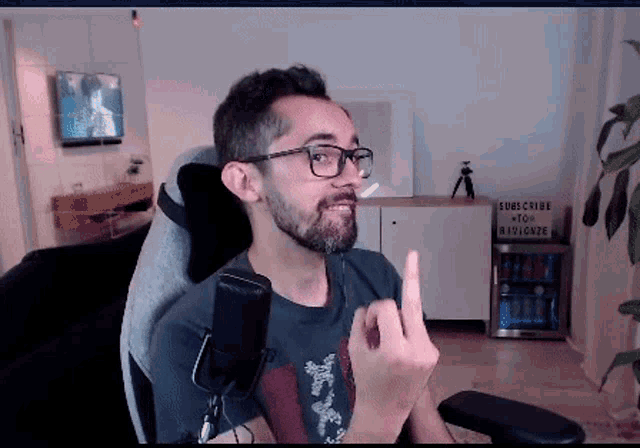 a man with glasses is giving the middle finger in front of a sign that says subscribe to rivionize