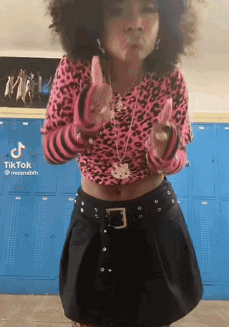 a girl is wearing a pink leopard print top and a black skirt .