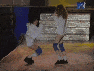 two women are dancing in front of a tv screen that says mtv