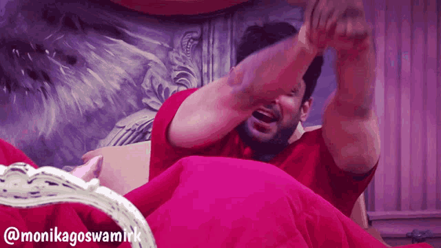 a man in a red shirt is laying on a bed with the name monikagoswamirk on the bottom