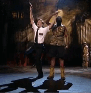 a man in a tie holds up a gun while dancing with another man