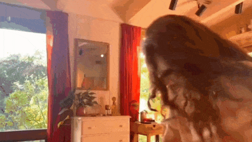 a woman is standing in front of a window in a room