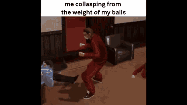 a man in a red tracksuit is dancing in a living room with other people .