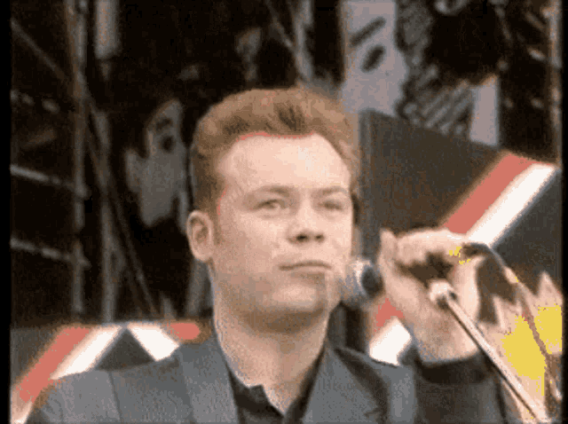 a man in a suit singing into a microphone with a blurred background