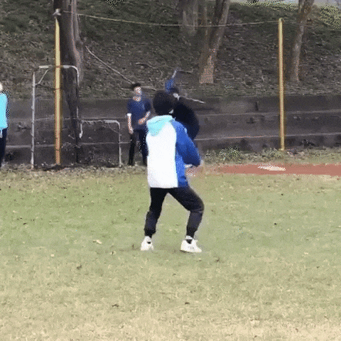 a person is throwing a baseball on a field while wearing a mask .