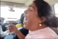 a woman is sitting in a car with her mouth open .
